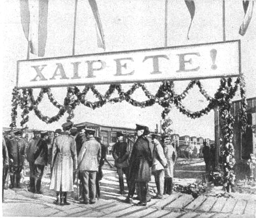 Η είσοδος του στρατοπέδου Γκαίρλιτς . Διακρίνεται πλήθος επισήμων και η φρουρά της πόλης για να υποδεχτεί τον ελληνικό στρατό. Υπάρχει μια μεγάλη επιγραφή στα ελληνικά που γράφει «ΧΑΙΡΕΤΕ» . Η φωτογραφία προέρχεται από το γαλλικό εβδομαδιαίο περιοδικό Le Miroir, τεύχος 153, 29 Οκτωβρίου 1916 και ο τίτλος της φωτογραφίας αποτυπώνει ανάγλυφα τα συναισθήματα των συμμάχων για την παράδοση του ελληνικού στρατεύματος, καθώς τιτλοφορείται «οι προδότες της Καβάλας εορτάζονται στη Γερμανία».